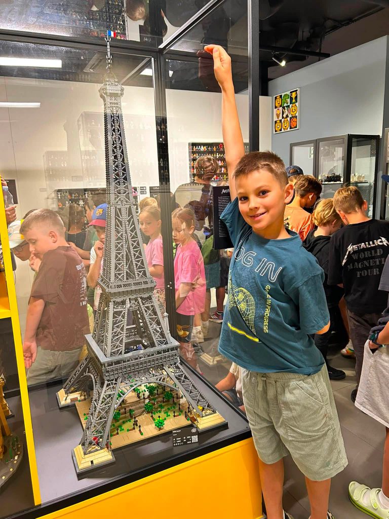 chłopczyk pozujacy do zdjęcia z wieżą lego