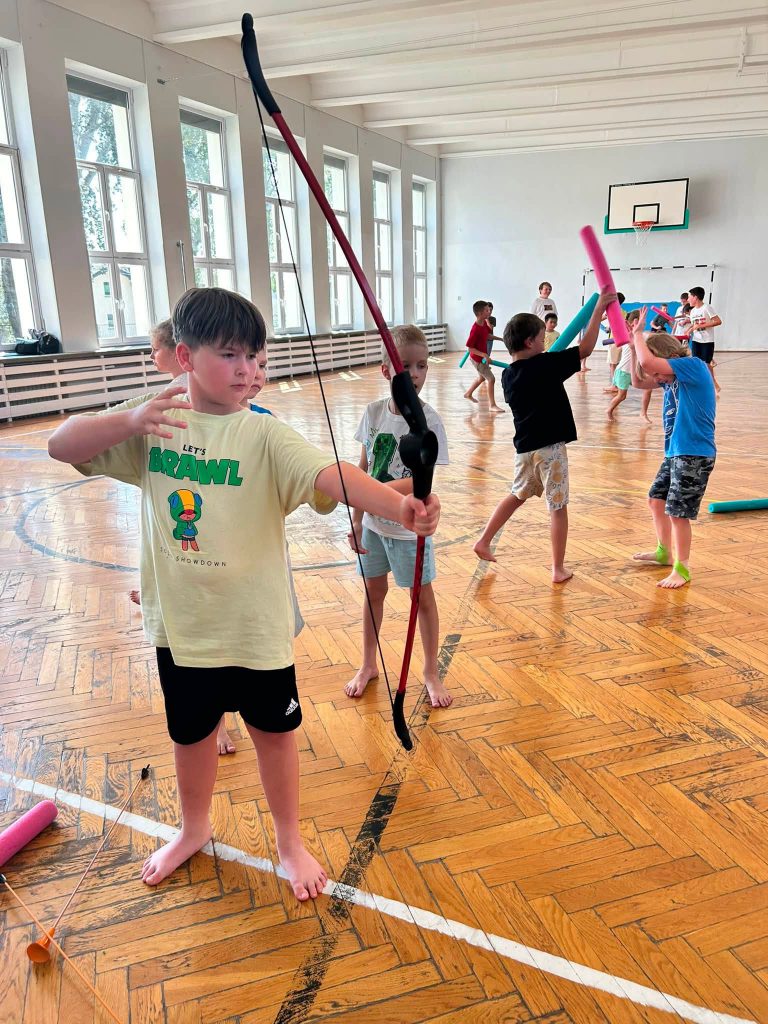 dzieci strzelają z zabakowych łuków
